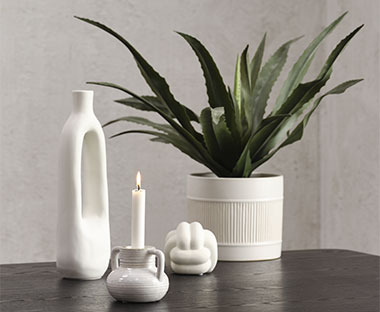 Váza, svietnik a kvetináč v bielej farbe položené na stole
