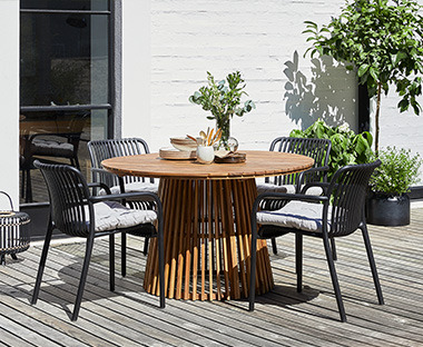 Drevený okrúhly záhradný stôl s čiernymi stoličkami