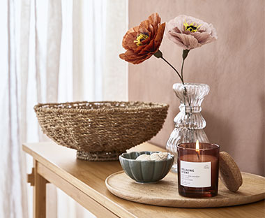 Malá sklenená váza s kvetmi, svietnik a misa z prírodného materiálu