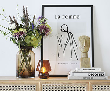 Čierny rám na fotky položený na komode spoločne s vázou a svietnikom