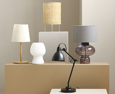 Rôzne sklenené lampy a lampy z prírodných materiálov položené vedľa seba