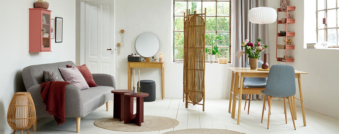 Jedáleň a obývacia izba s ružovou skrinkou, sivou rozkladacou pohovkou, bambusovým toaletným stolíkom a sivými jedálenskými stoličkami
