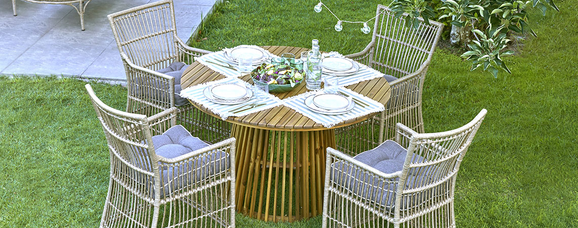 Okrúhly záhradný stôl a štyri stoličky na trávniku