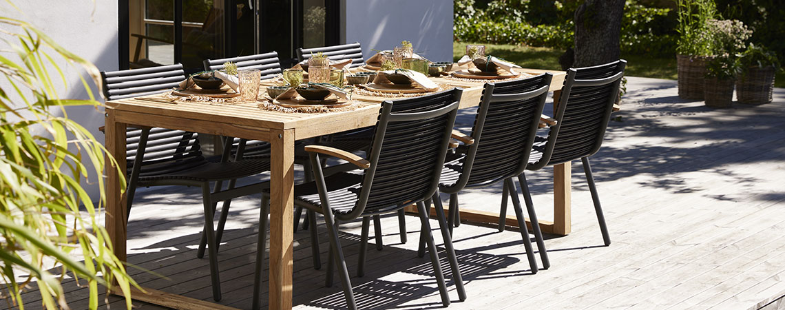 Drevený záhradný stôl a čierne kovové záhradné stoličky