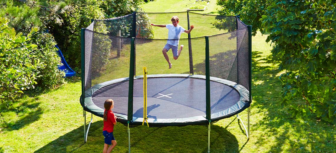 Deti, ktoré sa hrajú v záhrade na veľkej trampolíne