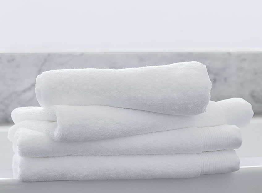 Biele uteráky položené na sebe v kúpeľni