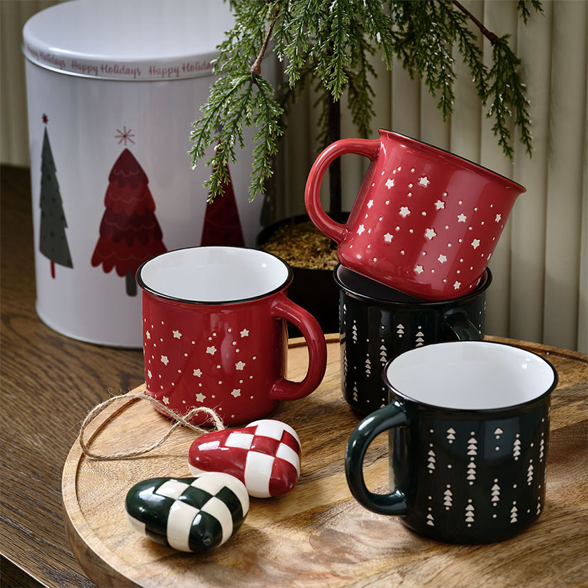 Festive Christmas mugs in red and green with holiday motifs and heart-shaped Christmas decorations 