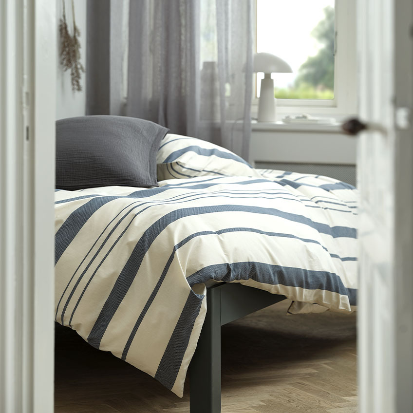 Bavlnené obliečky s bielymi a modrými pruhmi na posteli v spálni
