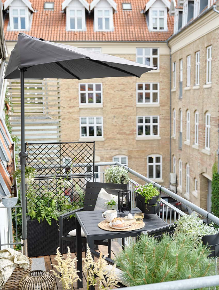 Balkónový slnečník na balkóne s menším záhradným nábytkom