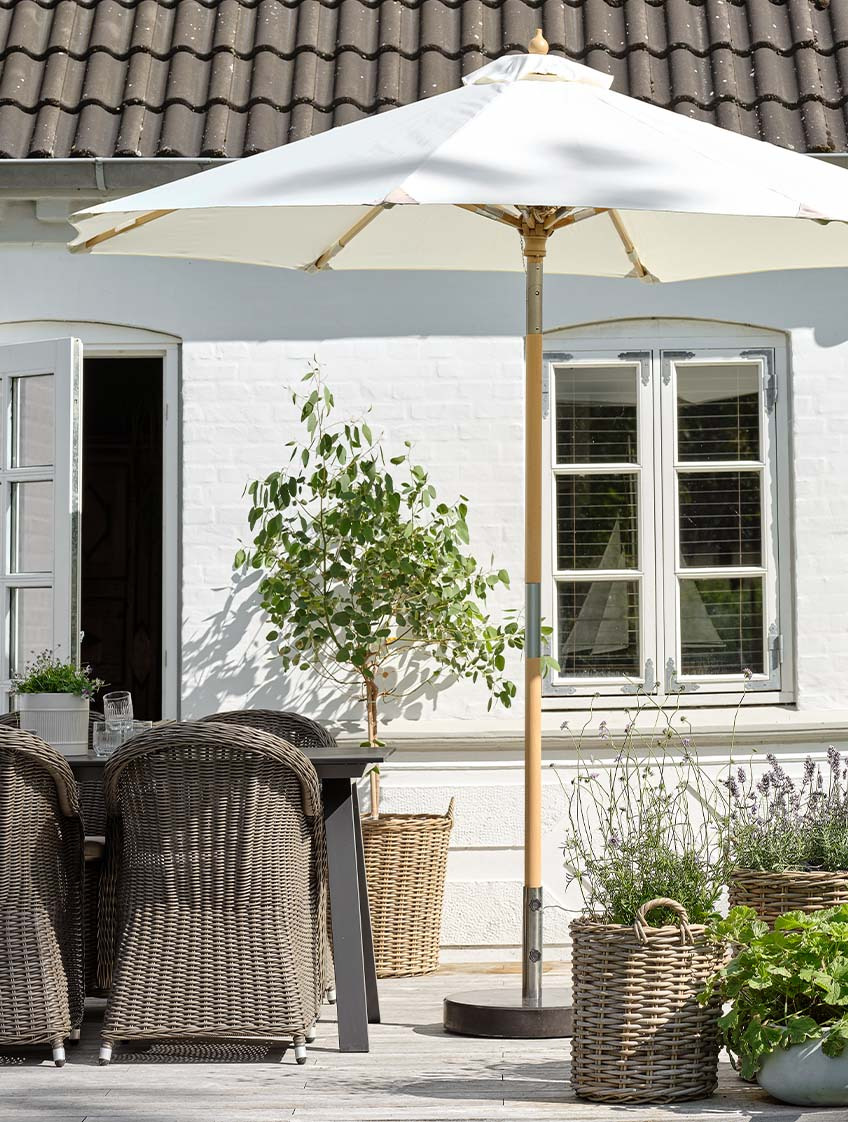 Sivobiely záhradný slnečník na terase so záhradným stolom a záhradnými stoličkami