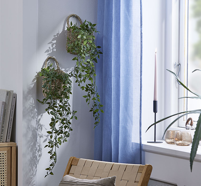 Dva košíky s umelými rastlinami visiace na stene obývačky