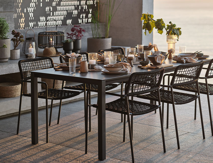 Záhradný stôl a stoličky pripravené na večeru na terase pri západe slnka