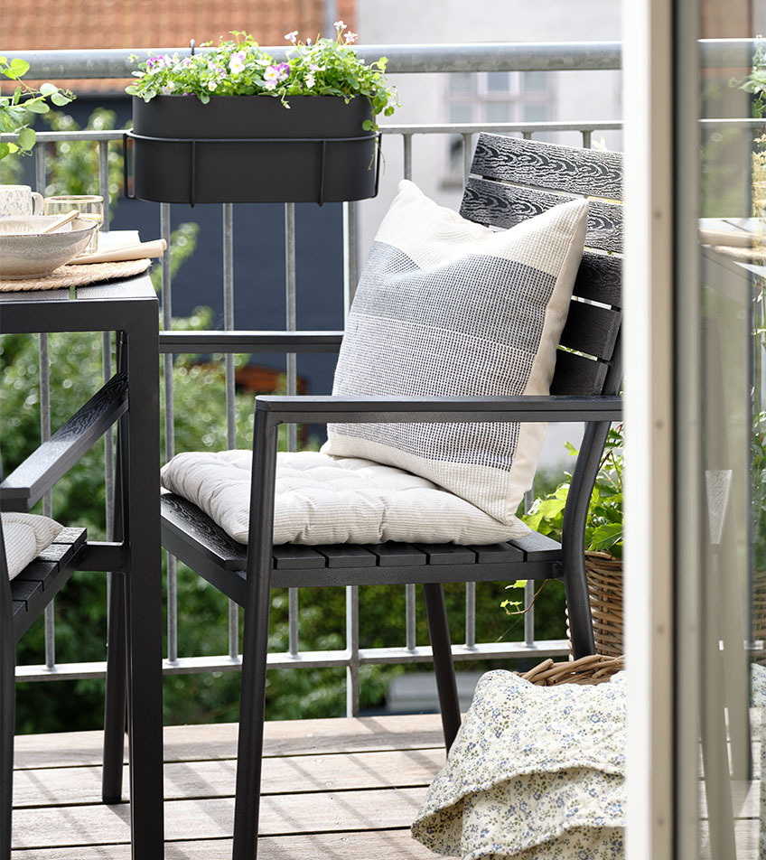 Čierna stohovateľná stolička s poduškami na balkóne
