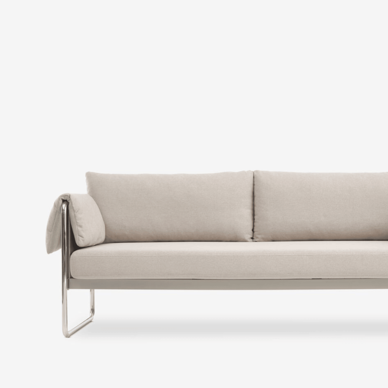 Classic sofas Close-up of a beige sofa with a chrome tubular frame and a bolster-style armrest, against a plain white background.
