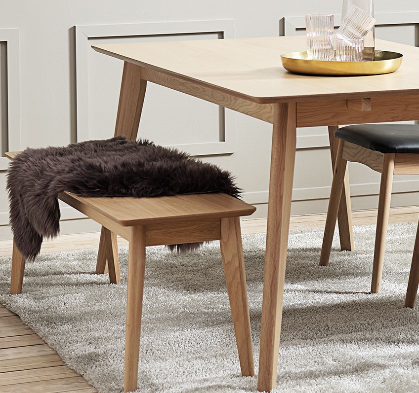 A dining room bench, half covered in a hide, at a dining table 