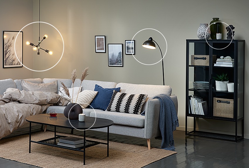 Duvet placed in corner sofa, pendant with light bulbs, modern floor lamp and display cabinet