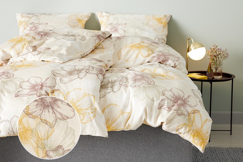 Posteľ s kvetovanými obliečkami v spálni s nočným stolíkom a lampou