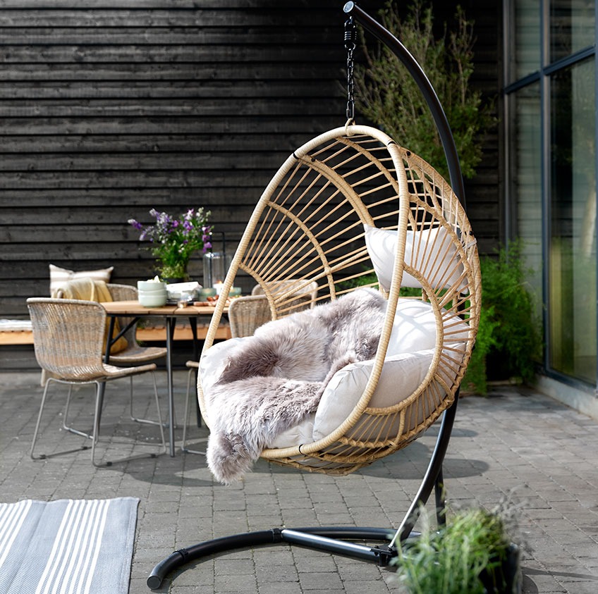 GJERN hanging chair is available in natural and black colour Patio with a hanging chair and dining set in the background