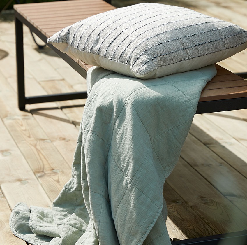 Drevená záhradná lavica s dekou a ozdobným vankúšom