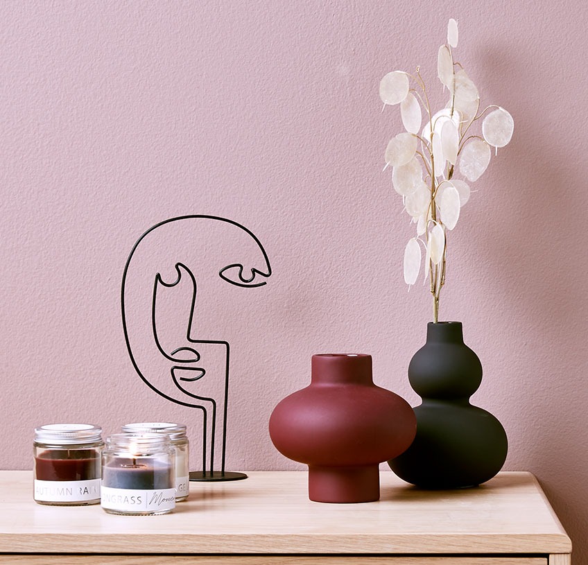 Red ADAM vase, black ROBERT vase, FRANZ sculpture and PAUL scented candles Flower vases on a table with a sculpture and three scented candles