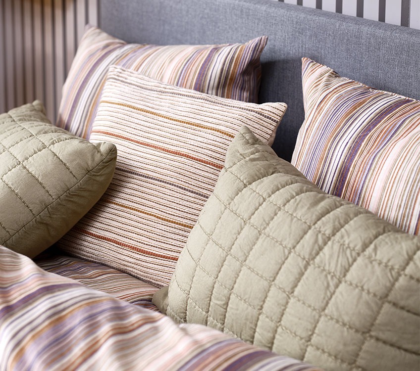 Striped bedlinen with striped decorative cushions and green pillows