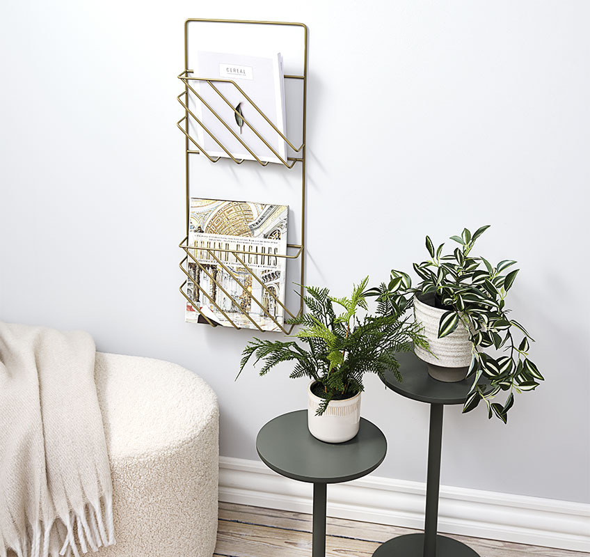 Dva odkladacie stolíky na rastliny a zlatý držiak na časopisy zavesený na stene 