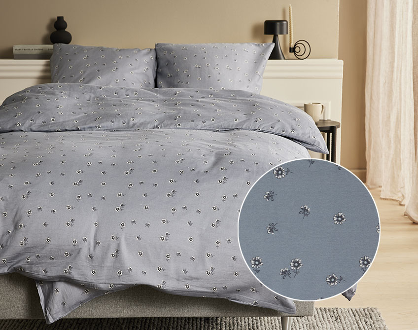 Saténové obliečky sivej farby s malými kvetmi na posteli