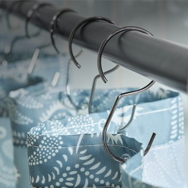 Close-up of chrome shower curtain rings clipped to a rod, holding a blue floral-patterned fabric shower curtain liner.