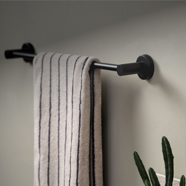 Matte black wall-mounted towel bar holding a folded beige towel with navy stripes, beside a potted cactus.