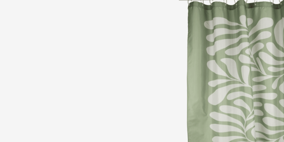 Sage green shower curtain with a white leaf pattern, hanging from a rod against a plain light background.