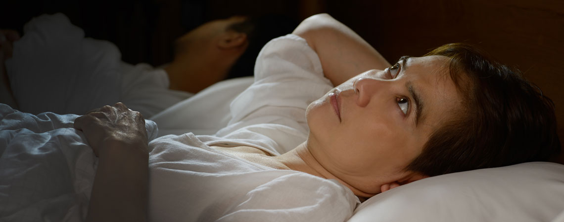 žena leží v posteli s otvorenými očami