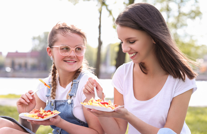 Two girls eating in a park in sunny weather